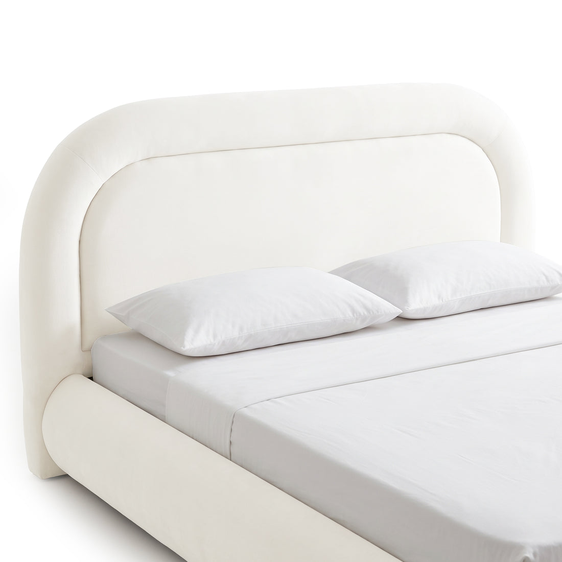 Close studio view of the rounded upholstered bed headboard, mattress, pillows, and side rail
