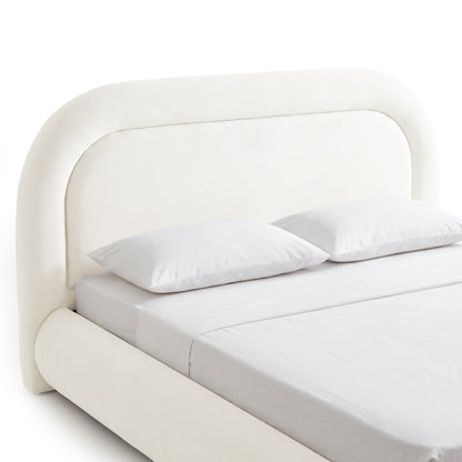 Close studio view of the rounded upholstered bed headboard, mattress, pillows, and side rail