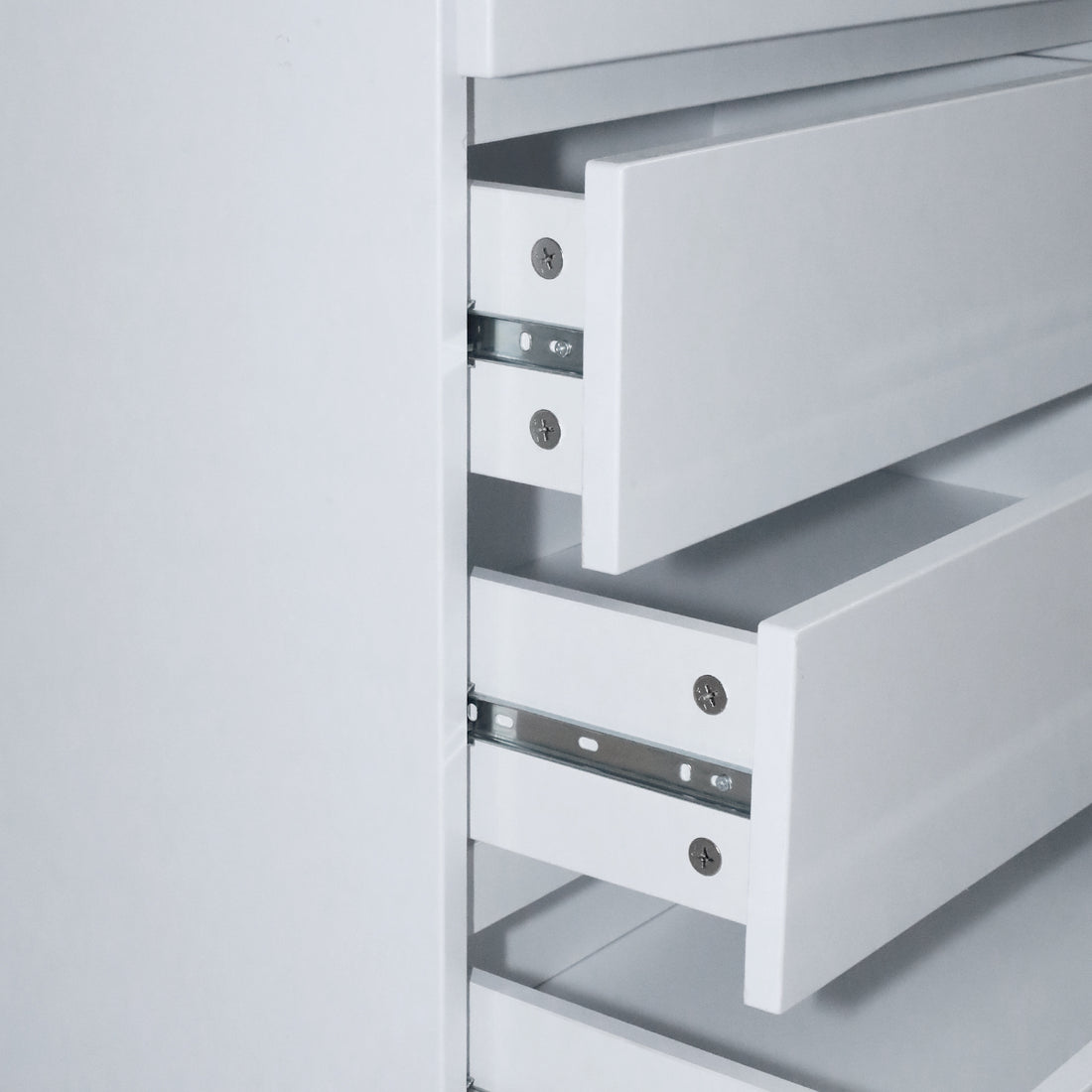 Close-up of two open white drawers showing metal rails on white background