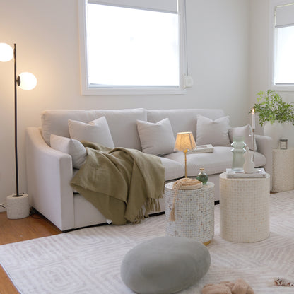 Light-colored sofa styled in a bright modern living room with pillows and decor
