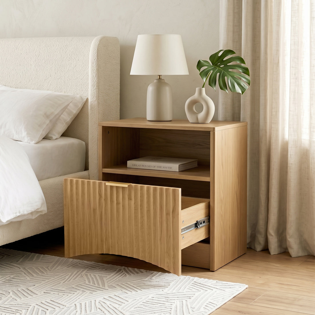 Light wood nightstand styled next to a bed in a cozy bedroom.