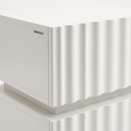 Partial view of a white furniture piece with textured front on a white background.