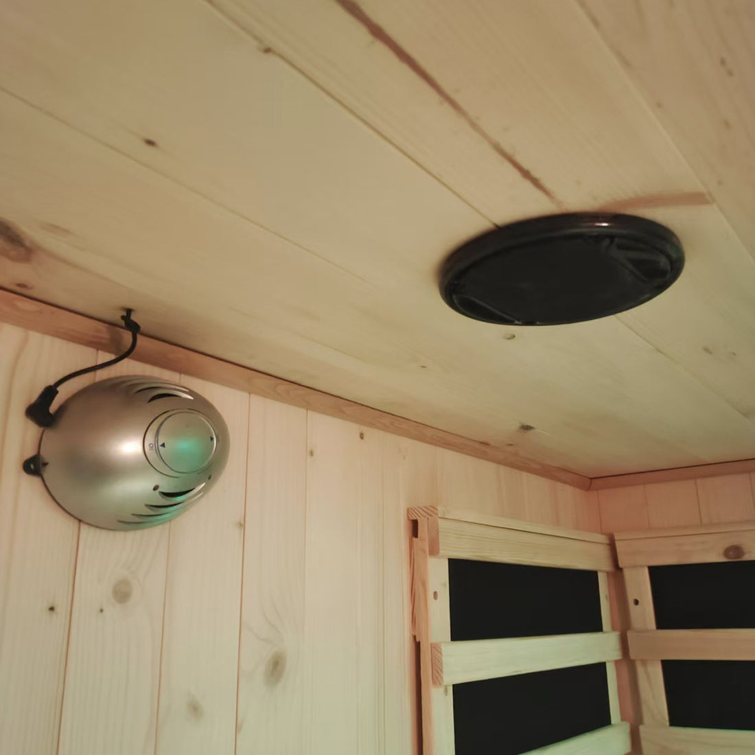 The Luxo Kiima 3 Person Hybrid Finnish Outdoor Sauna showcases a tongue-and-groove interior with a ceiling speaker and wall-mounted control module, complemented by a slatted wooden bench.