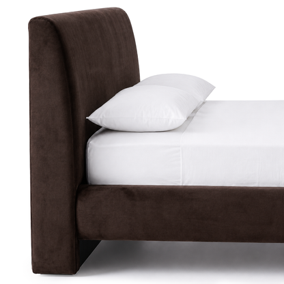 Side view of upholstered bed showing headboard, frame, and bedding on white background