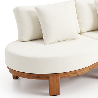 Partial view of a curved sectional sofa with white cushions and a wooden base on a white background.