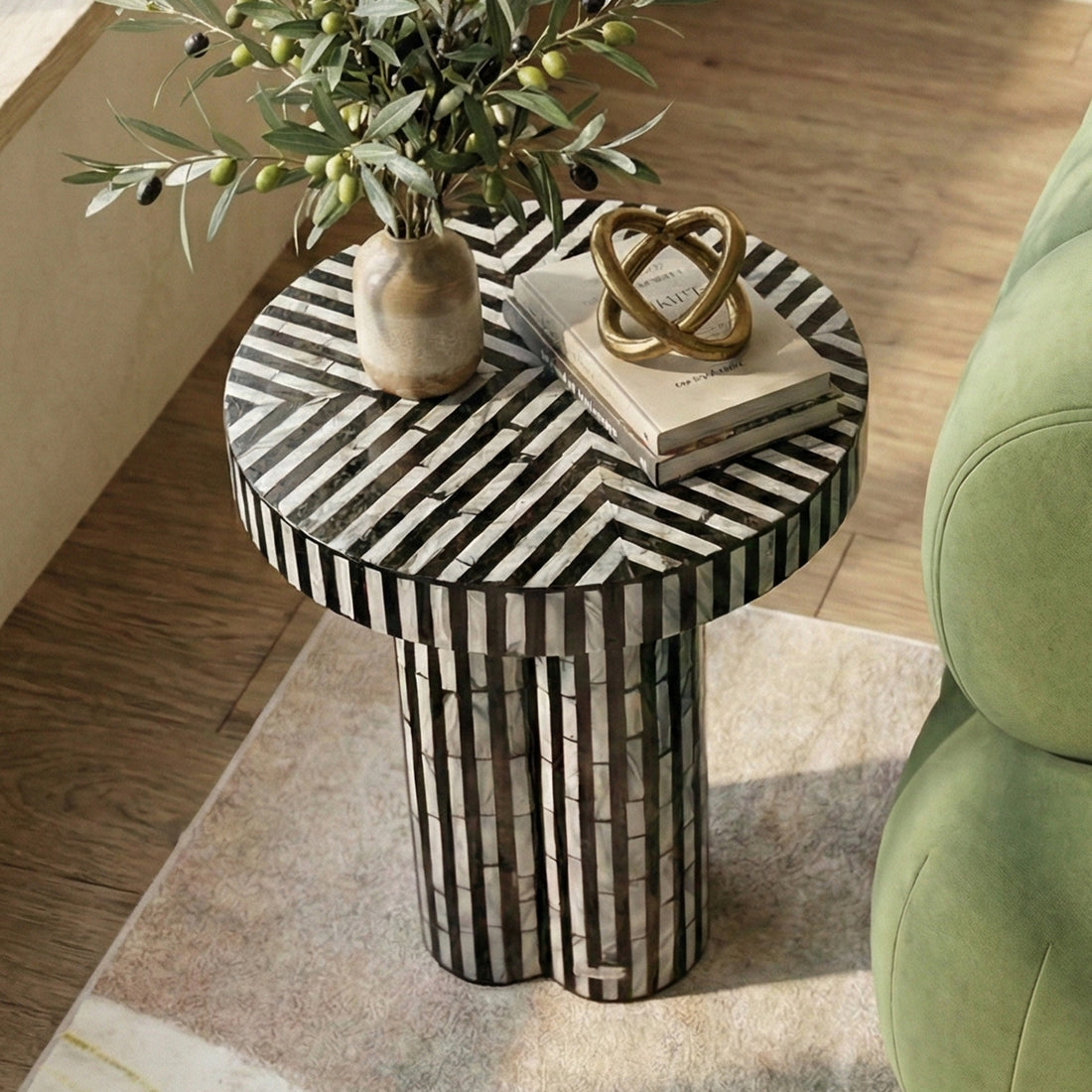 Modern round side table in room next to green sofa with decor items