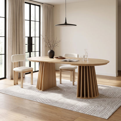 Oval wooden dining table in a modern styled dining room with chairs and decor