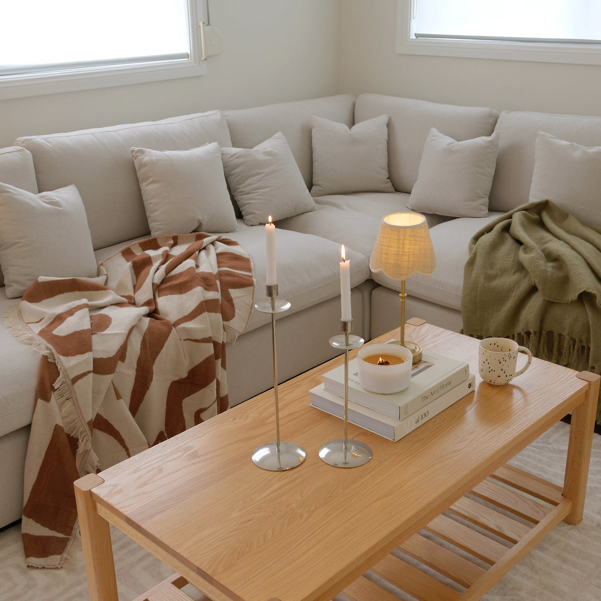 Wood coffee table styled in a modern living room with sectional sofa in the background