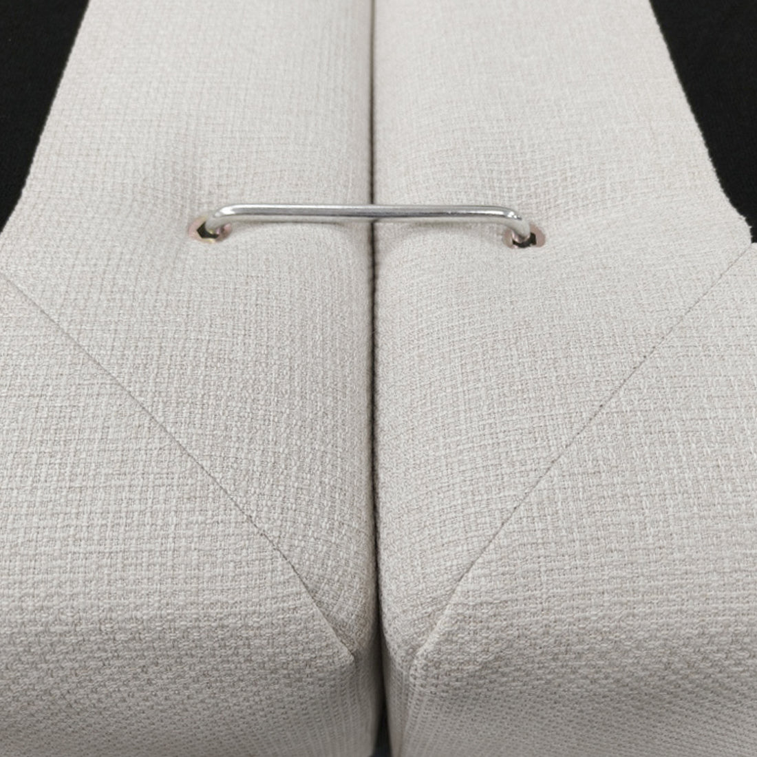 Close-up of beige upholstered cushions joined by a metal connector bar