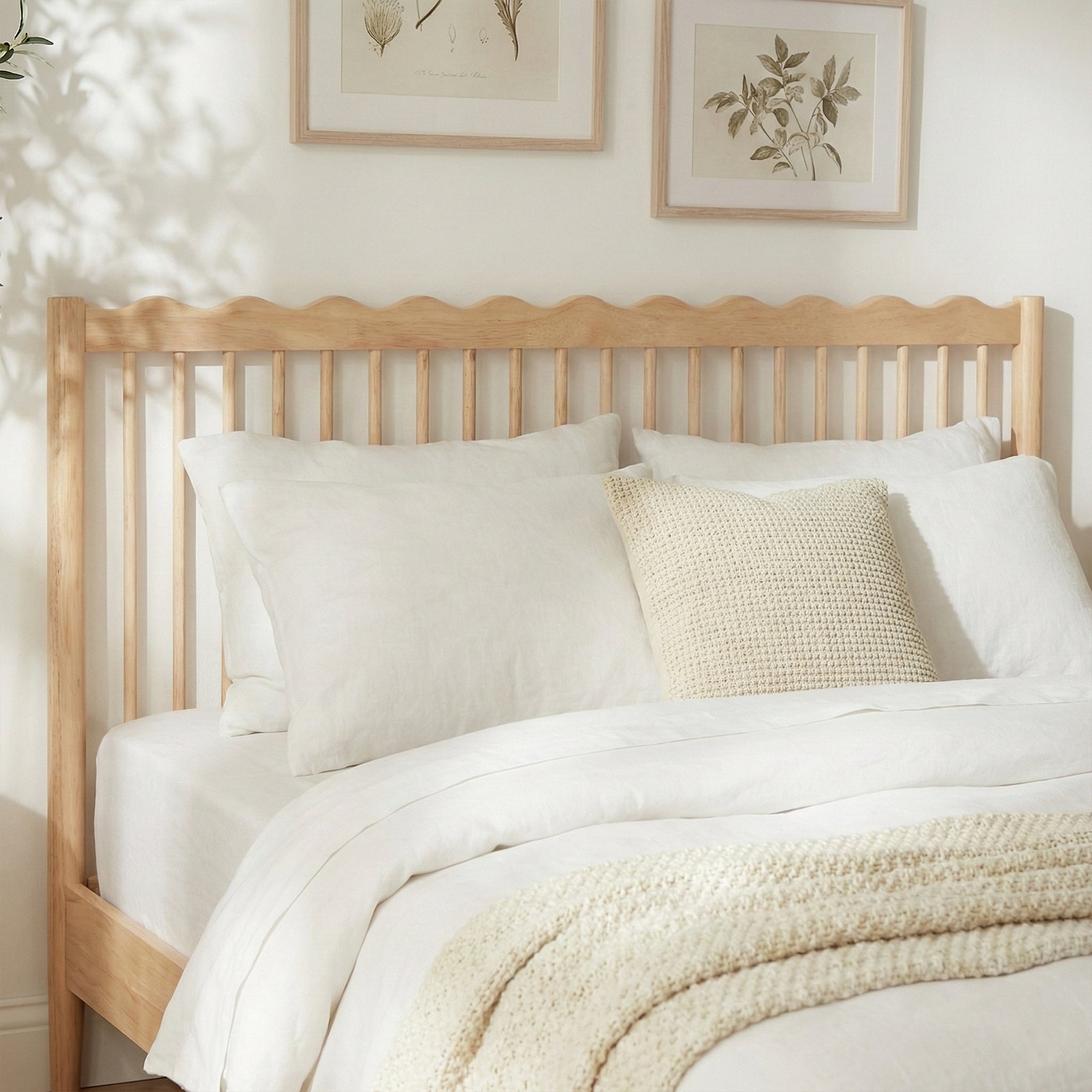 Wooden bed frame with white bedding in styled bedroom, slightly zoomed