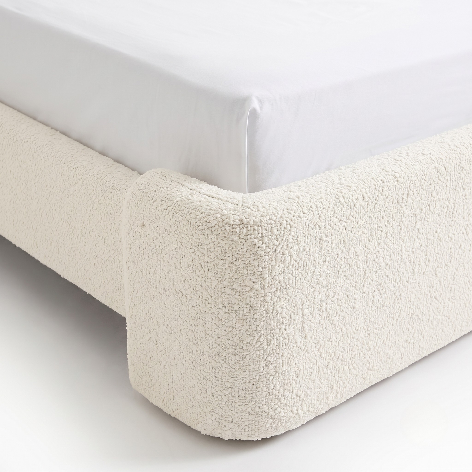 Corner detail of an upholstered bed frame on a white background