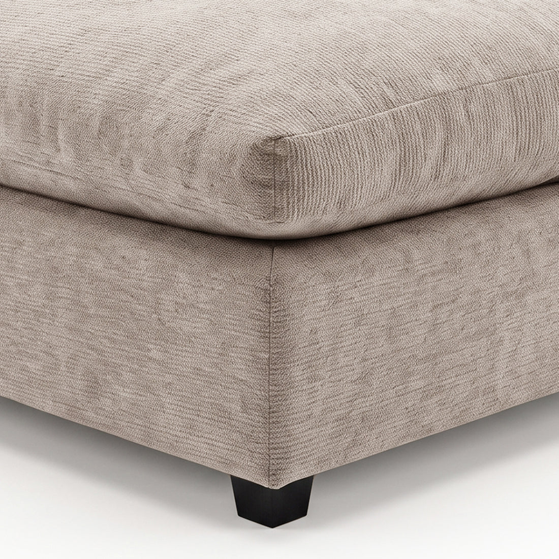 Close-up of a beige upholstered ottoman corner on a white background.