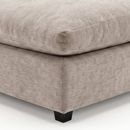 Close-up of a beige upholstered ottoman corner on a white background.