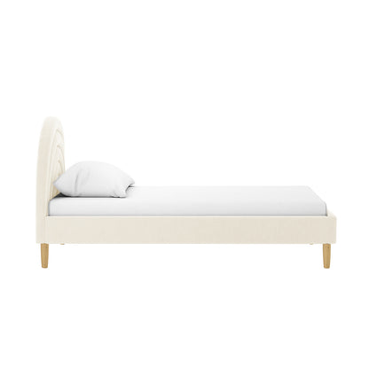Estilla Velvet Rainbow Bed in Beige features a softly arched, channel-stitched headboard with matching low foot and side rails, completed with a white mattress and pillow on tapered wooden legs.