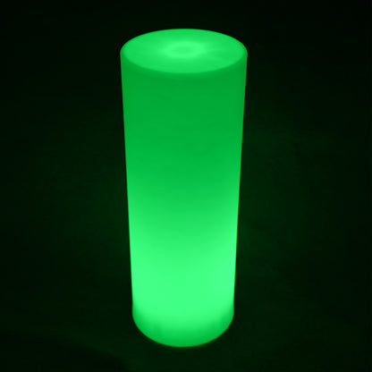 16 Colour Outdoor LED Bollard Light in Multicolour, glowing bright green, stands in a dark space. Tall, smooth-sided cylinder design, ideal for atmospheric outdoor lighting on pathways and gardens.