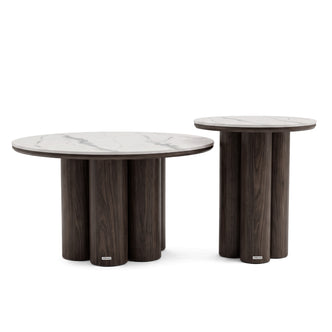 Two modern nesting tables with dark wood cylindrical bases and light marble-like round tops on a white background