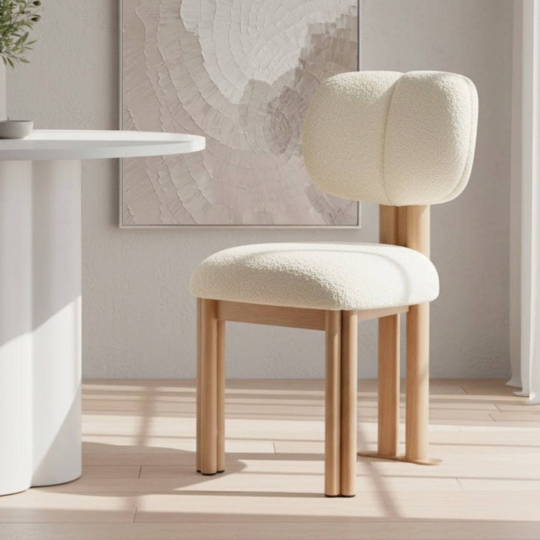 Norii Boucle Fabric Dining Chair in Cream White with plush, off-white boucle cushion and light-wood legs in a minimalist, Scandinavian-inspired interior corner, complementing a textured wall art piece.