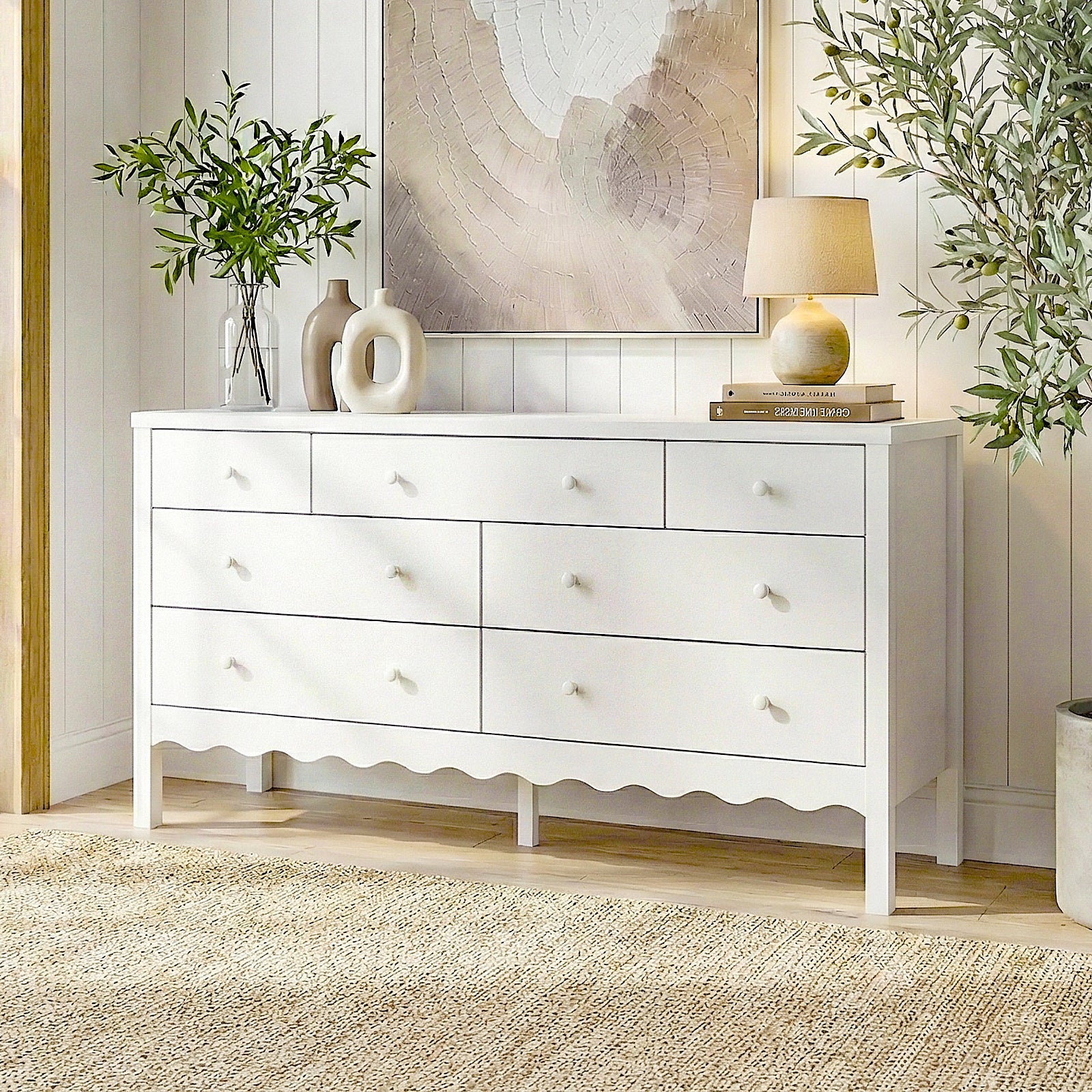 White nine-drawer dresser in a styled room with vases, lamp, books, and wall art
