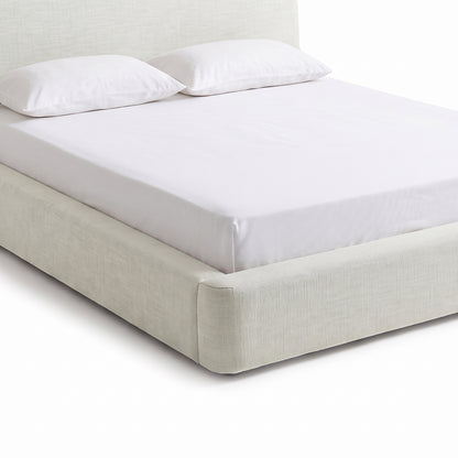 Angled partial view of an upholstered bed on a white background
