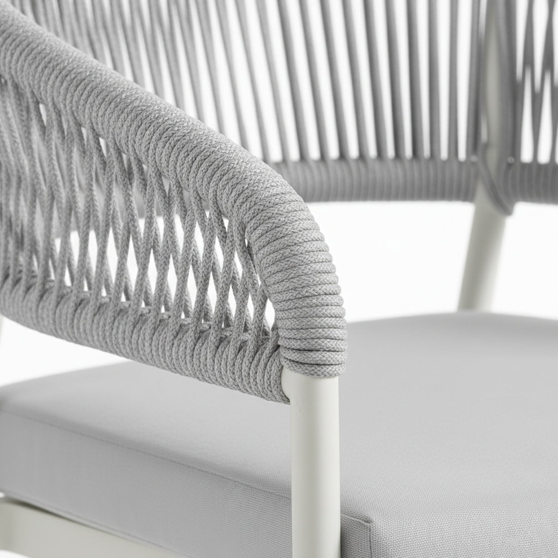 Close-up of the Coastal Outdoor Rope Dining Chairs Set of 2 in White, showing a tubular metal frame with gray braided cord on the armrest and a matching upholstered seat cushion.