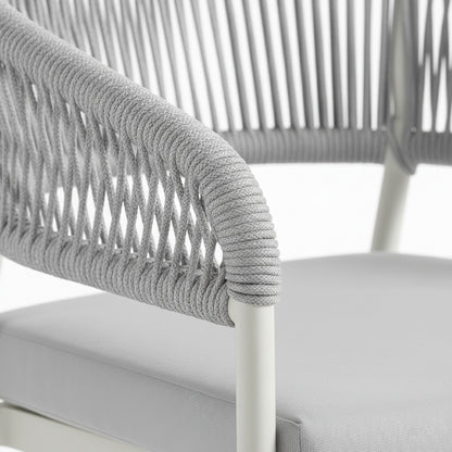 Close-up of the Coastal Outdoor Rope Dining Chairs Set of 2 in White, showing a tubular metal frame with gray braided cord on the armrest and a matching upholstered seat cushion.