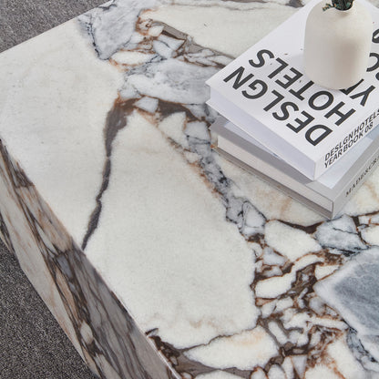Close-up of the Solene 100cm Coffee Table in Blue Galaxy on a low-pile carpet, featuring a marble surface with unique veining, a stack of design books, and a simple ceramic vase with dried stems.