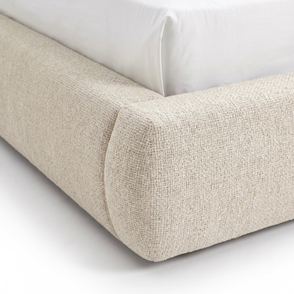 Close-up of the corner of an upholstered bed with textured beige fabric