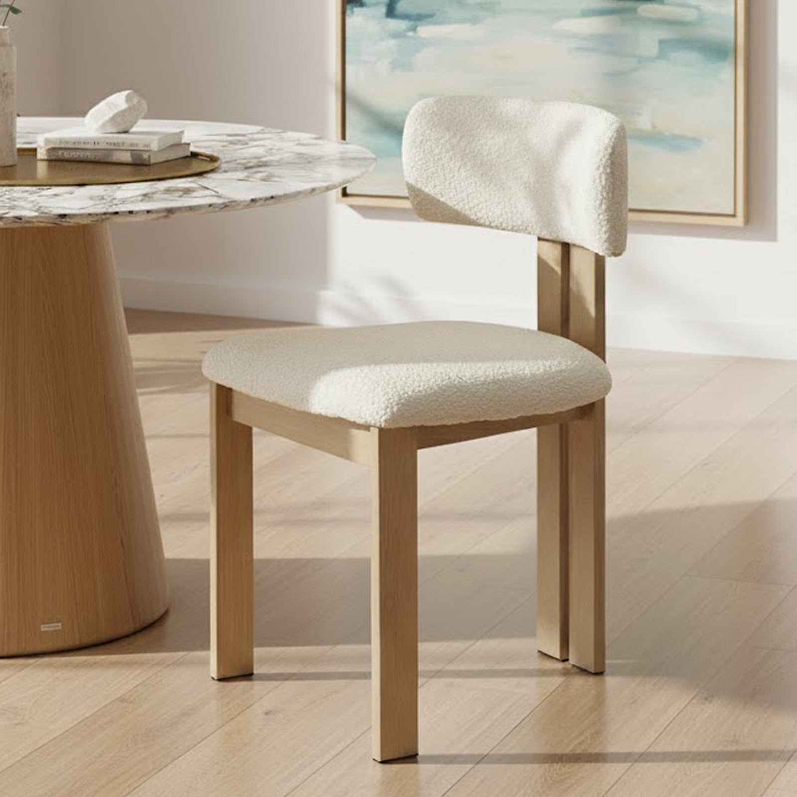 Haleo Curved Boucle Dining Chair Set of 2 in Cream White features a wooden frame with soft boucle upholstery on the seat and backrest, elegantly paired with a white marble-topped dining table.