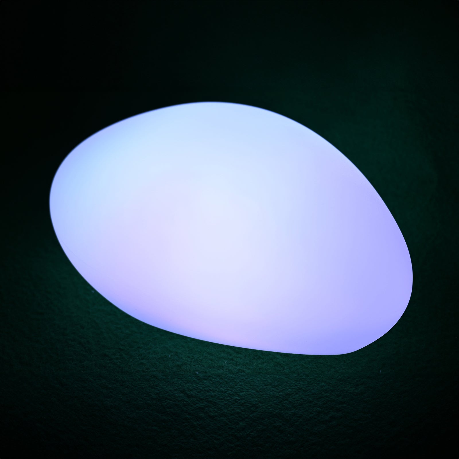 Solar Charging Outdoor LED Rock Light on a textured surface, glowing softly with color-shifting LED light, resembling a natural stone. Ideal for garden ambiance and path illumination.