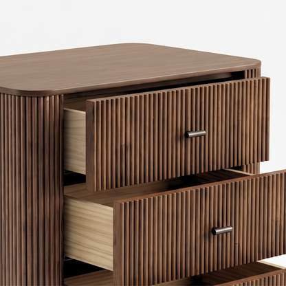 Partial close-up of a wooden dresser with fluted drawer fronts on a white background