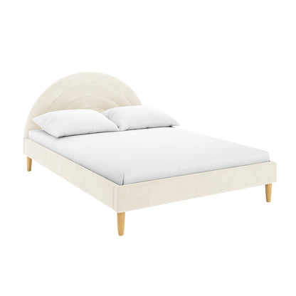 Estilla Velvet Rainbow Bed in Beige features a semi-circular headboard with arch details, upholstered in soft velvet, supported by tapered wood legs. Includes white mattress and pillows on the platform.