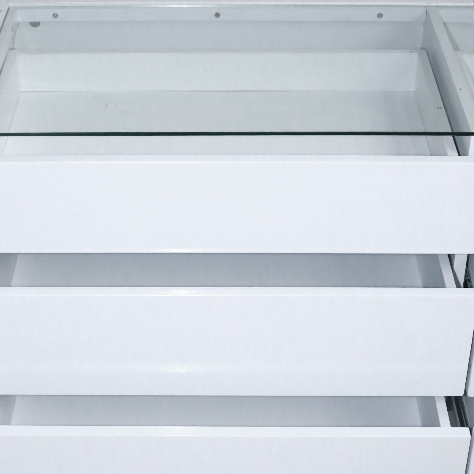 Close-up of three white drawers partially open showing internal construction on white background