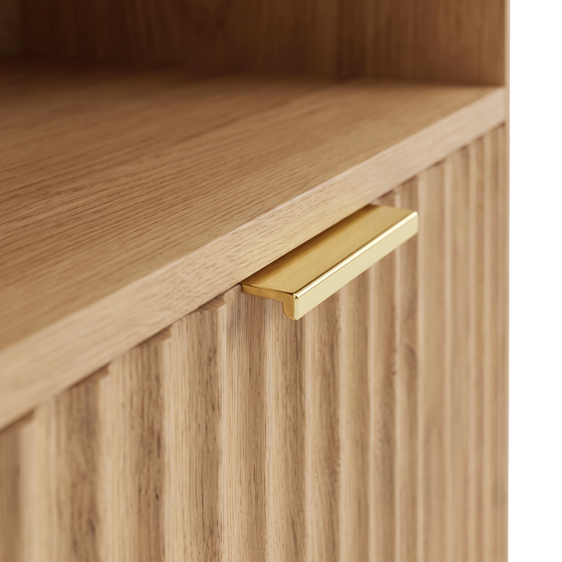 Close-up of a light wood furniture corner with grooved front and gold handle.