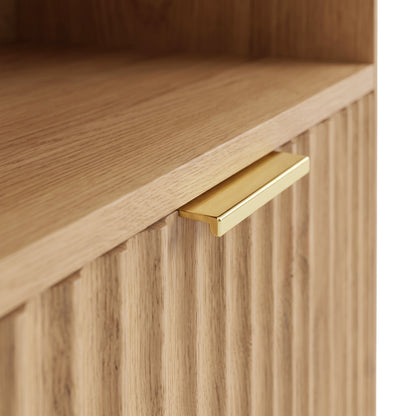 Close-up of a light wood furniture corner with grooved front and gold handle.