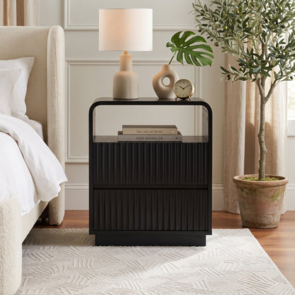 Black nightstand styled in a cozy bedroom beside a bed with decor and a lamp