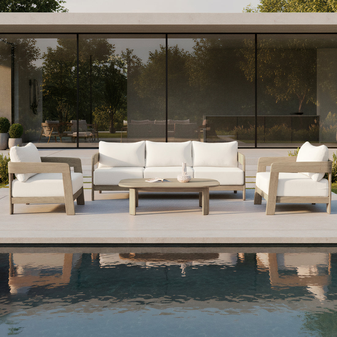 Elani 5-Seater Acacia Hardwood Outdoor Sofa Set in Cream features a wooden coffee table, plush-cushioned sofa, and two armchairs, all set beside a reflecting pool and glass doors.