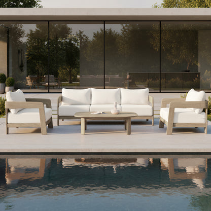 Elani 5-Seater Acacia Hardwood Outdoor Sofa Set in Cream features a wooden coffee table, plush-cushioned sofa, and two armchairs, all set beside a reflecting pool and glass doors.