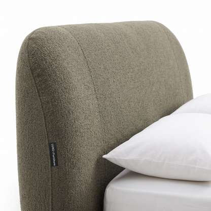 Close-up of upholstered bed headboard corner with bedding