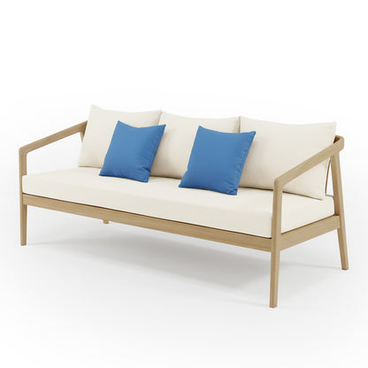 Delva 4 Seater Hardwood Acacia Outdoor Sofa Set in Cream features a minimalist three-seat bench with a light wood frame, creamy off-white cushions, and two bright blue throw pillows for a contemporary outdoor look.
