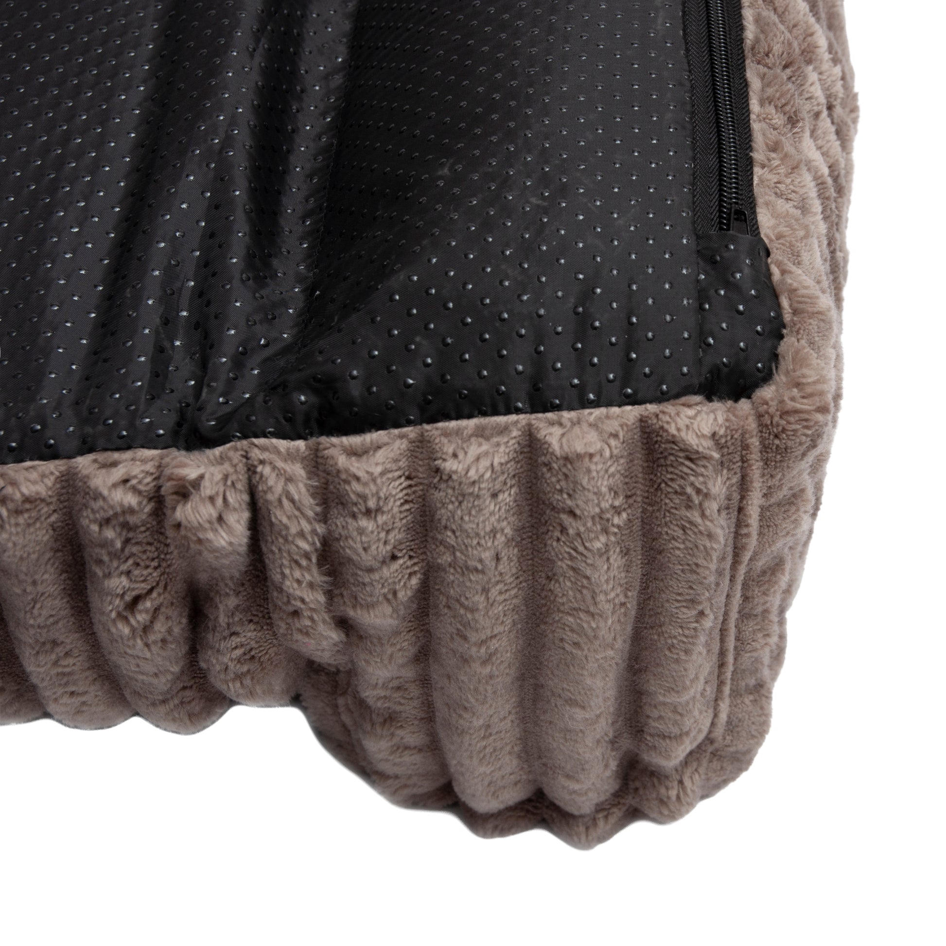 Close-up of brown ribbed fabric and black zipper on pet bed edge against white background