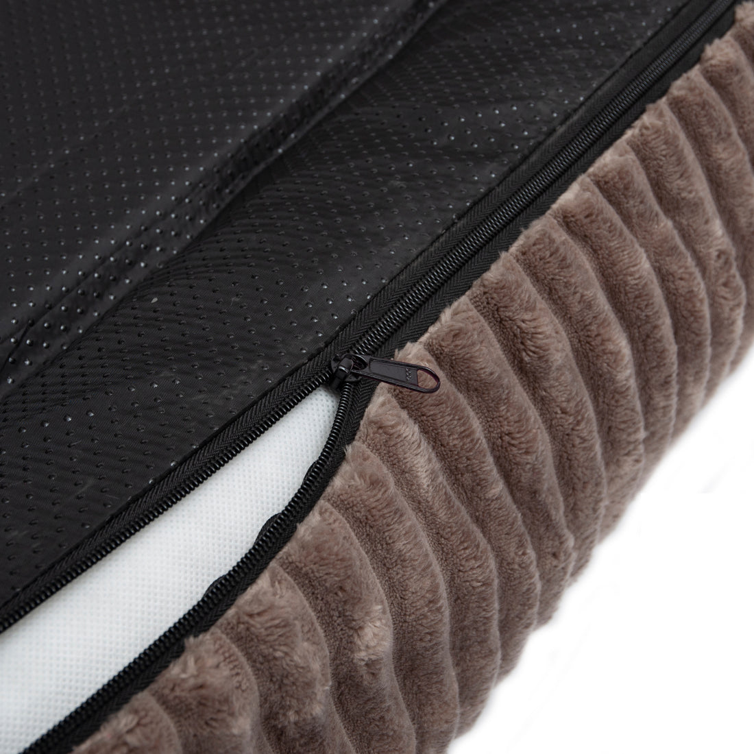 Close-up of soft brown quilted fabric with partially open zipper revealing white interior and black non-slip surface