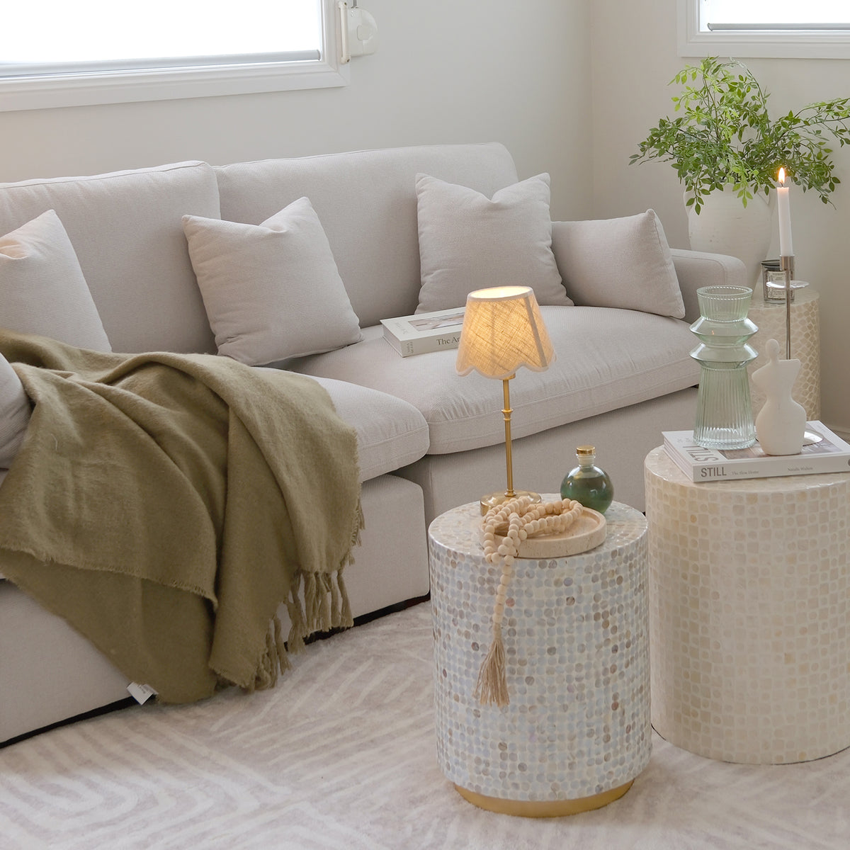 Styled living room corner with mosaic side tables, sofa, lamp, and decor