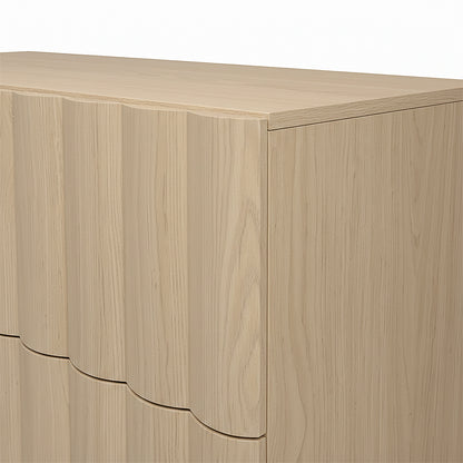 Close-up of the top corner of a light wood dresser on white background