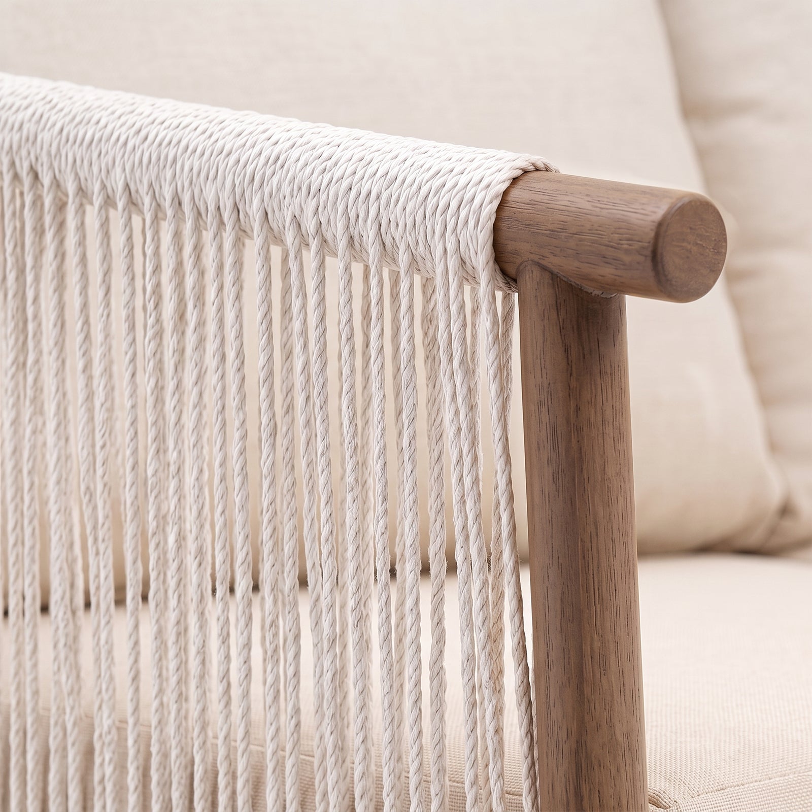 Close-up of wooden armrest and woven rope detail on a chair in a room setting