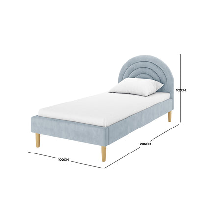Estilla Velvet Rainbow Bed in Ice Blue features a gently arched headboard, pale blue/grey upholstery, and turned wooden legs, providing a cozy, stylish sleep space with ample under-bed storage.