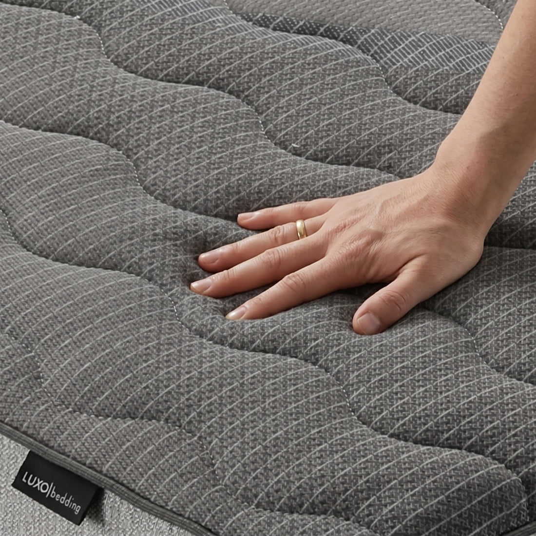Close-up of hand pressing mattress fabric with brand label