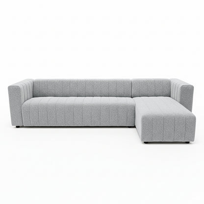 Parisa 4 Seater Tufted Boucle Sofa with Chaise in Light Grey, featuring an L-shape, low wide arms, vertical channel tufting, and a right-hand chaise for relaxed lounging.