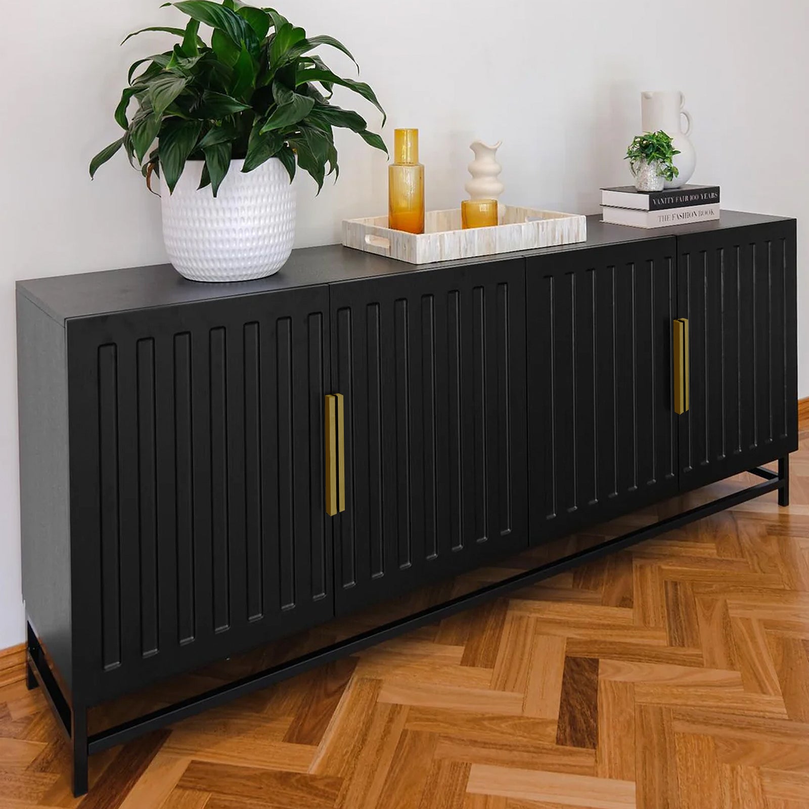 Black sideboard styled in living room with plant and decor