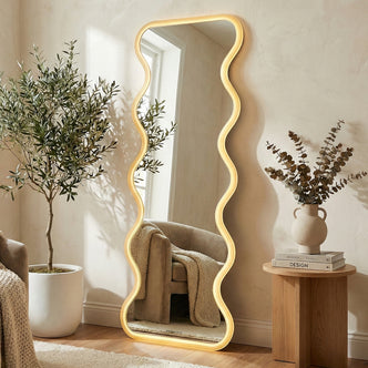 Wavy LED mirror leaning against a wall in a styled living room with plants and decor