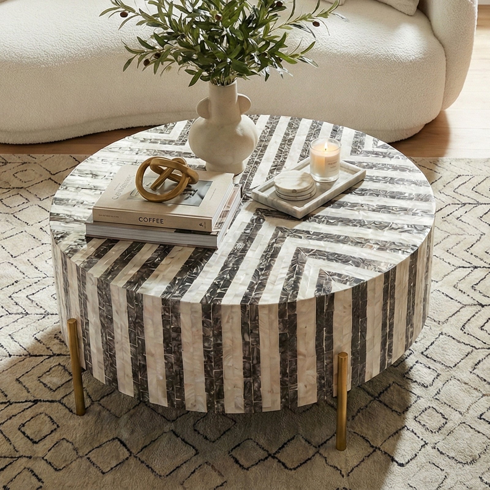 Round black and white striped coffee table styled with books, vase and decor in living room
